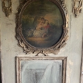 Tableau ovale représentant un couple dans un décor pastoral, encadré de feuilles d'or ouvragées sur un mur gris patiné, évoquant le charme intemporel du trumeau « Miroir » du XIXe siècle. Brocante 93