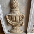 Sculpture décorative richement ouvragée et patinée par le temps, réalisée sur un panneau de bois, en forme d’urne classique ornée de drapés — qui rappelle le savoir-faire artisanal raffiné que l’on retrouve sur un miroir trumeau du XIXe siècle. Brocante 93
