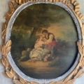 Un miroir trumeau richement décoré du XIXe siècle présente un tableau encadré rappelant un chef-d'œuvre de cette époque, représentant un couple assis en plein air, avec des fleurs à leurs pieds et des arbres en arrière-plan, évoquant l'élégance et le charme caractéristiques des modèles classiques de miroirs trumeau. Brocante 93