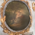 Un tableau ovale représentant un couple assis côte à côte, encadré de motifs ouvragés à la feuille d'or et d'argent, dans le style raffiné du XIXe siècle, qui rappelle l'élégant miroir trumeau du XIXe siècle. Brocante 93