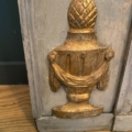 Urne décorative dorée, ornée d'un tissu drapé sur du bois gris vieilli, évoquant l'élégance du XIXe siècle, posée sur un parquet : un complément parfait au miroir trumeau du XIXe siècle. Brocante 93