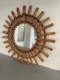 Le « Miroir soleil bambou 1950 » se distingue par son cadre décoratif en bambou, orné de deux rangées de tiges de bambou disposées selon un motif rayonnant saisissant, qui incarne à la perfection l'élégance intemporelle d'un miroir soleil classique des années 1950. Brocante 93