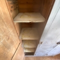Un vestiaire en bois datant de 1940, comportant quatre étagères vides, vu d'en haut et placé à côté d'une porte peinte en blanc. Brocante 93