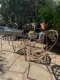 Trois chaises en fer forgé de 1940, richement décorées, trônent sur une terrasse ensoleillée, entourées de plantes verdoyantes et de succulentes en pot, évoquant l'élégance intemporelle du mobilier vintage. Brocante 93