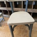 Le « Bureau d’enfant & chaise 1960 », composé d’une chaise en bois dotée d’une assise et d’un dossier beiges associés à des pieds foncés, trône sur un parquet à côté d’étagères en bois : il est parfait pour servir de bureau d’enfant. Brocante 93