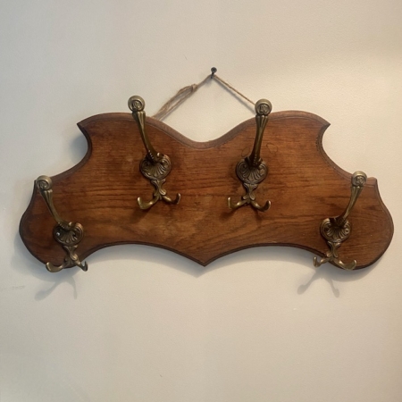 Un « Porte-serviettes 1960 », un porte-manteau vintage en bois muni de cinq crochets en laiton ouvragés, est accroché à un mur blanc. Brocante 93