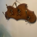 Porte-serviettes 1960 : une plaque murale en bois ornée de cinq patères en laiton décorées, fixée sur un mur de couleur crème. Brocante 93