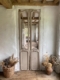 Portes d’ascenseur de 1940 : portes d’ascenseur anciennes en bois, ornées de panneaux miroirs, entre des murs blancs. Brocante 93