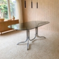 Table à manger des années 1970, dotée d'un plateau rectangulaire en verre fumé et d'un piètement chromé incurvé. Brocante 93