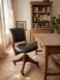 Fauteuil de bureau américain des années 1930 : fauteuil de bureau en cuir foncé, doté d'un piètement pivotant en bois et de roulettes. Brocante 93