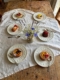 Six assiettes à dessert vintage « Assiettes à dessert » de Wedgwood, datant de 1960, disposées autour d'un vase de fleurs. Brocante 93