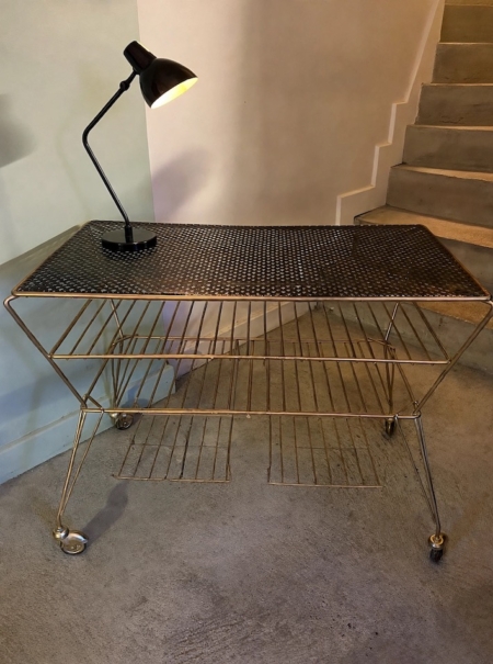 Table basse des années 1950 : un chariot de service vintage en métal, doté d'un plateau perforé et d'une lampe de bureau noire. Brocante 93