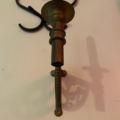 Un lustre de piano datant de 1960, orné d'une bougie orange, projette une ombre sur le fond blanc. Brocante 93