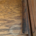 Gros plan sur la surface d'un « Bureau américain à cylindre » de 1930 présentant une tache circulaire et un bord ébréché. Brocante 93