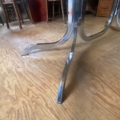 Table à manger chromée aux lignes courbes des années 1970, posée sur un parquet. Brocante 93