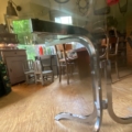Table à manger des années 1970, dotée d'un plateau en verre et d'un piètement chromé incurvé, caractéristique de cette décennie. Brocante 93