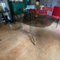 Table à manger vintage des années 1970, avec un plateau en verre fumé et un piètement en métal chromé. Brocante 93
