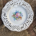 Assiette à dessert vintage blanche des années 1950, avec un bord ajouré et un motif floral central. Brocante 93