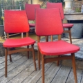 Quatre chaises de salle à manger vintage rouges « Chaises Skai 1960 » aux pieds en bois, disposées sur une terrasse en bois. Brocante 93