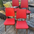 Quatre chaises vintage rouges « Skai » des années 1960, dotées de pieds en bois, disposées sur une terrasse en bois. Brocante 93