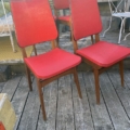 Quatre chaises vintage rouges « Chaises Skai 1960 » aux pieds en bois, disposées sur une terrasse en bois. Brocante 93