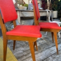Deux chaises vintage « Chaises Skai » de 1960, en bois, avec des assises rouge vif, disposées sur une terrasse en bois. Brocante 93