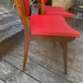 Deux chaises vintage « Chaises skai » de 1960, en bois, avec des assises rouge vif, disposées sur une terrasse en bois. Brocante 93