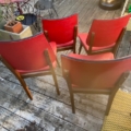 Quatre chaises vintage « Chaises skai » de 1960, en bois, avec des assises rouges, disposées sur une terrasse en bois. Brocante 93