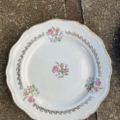 Assiettes plates de 1950 : assiette à dîner blanche aux bords festonnés rehaussés d'une bordure dorée et ornée de bouquets de fleurs. Brocante 93