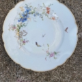 Assiettes plates vintage des années 1950, avec une bordure dorée et des motifs floraux et de papillons. Brocante 93