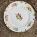 Assiettes plates vintage de 1950, de couleur blanche, ornées de motifs floraux et d'un bord doré. Brocante 93