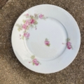Assiettes plates de style vintage des années 1950, de couleur blanche, ornées d'un motif de roses roses et de feuilles vertes. Brocante 93