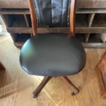 Fauteuil de bureau américain des années 1930 : un fauteuil pivotant en bois, doté d'une assise et d'un dossier rembourrés de couleur foncée. Brocante 93