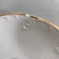 Tasses à café des années 1960 : soucoupe vintage blanche, motif de volutes en relief, bord doré, bord ébréché. Brocante 93